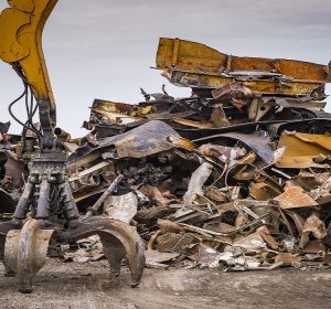 Large tracked excavator working a steel pile at a metal recycle yard, France